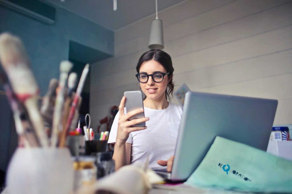 Girl taking a break from her computer to connect with paint brushes in the foreground.