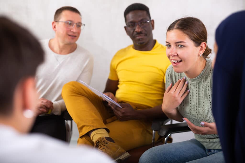 Cheerful young girl having a friendly debate with colleagues of different ages and nationalities.