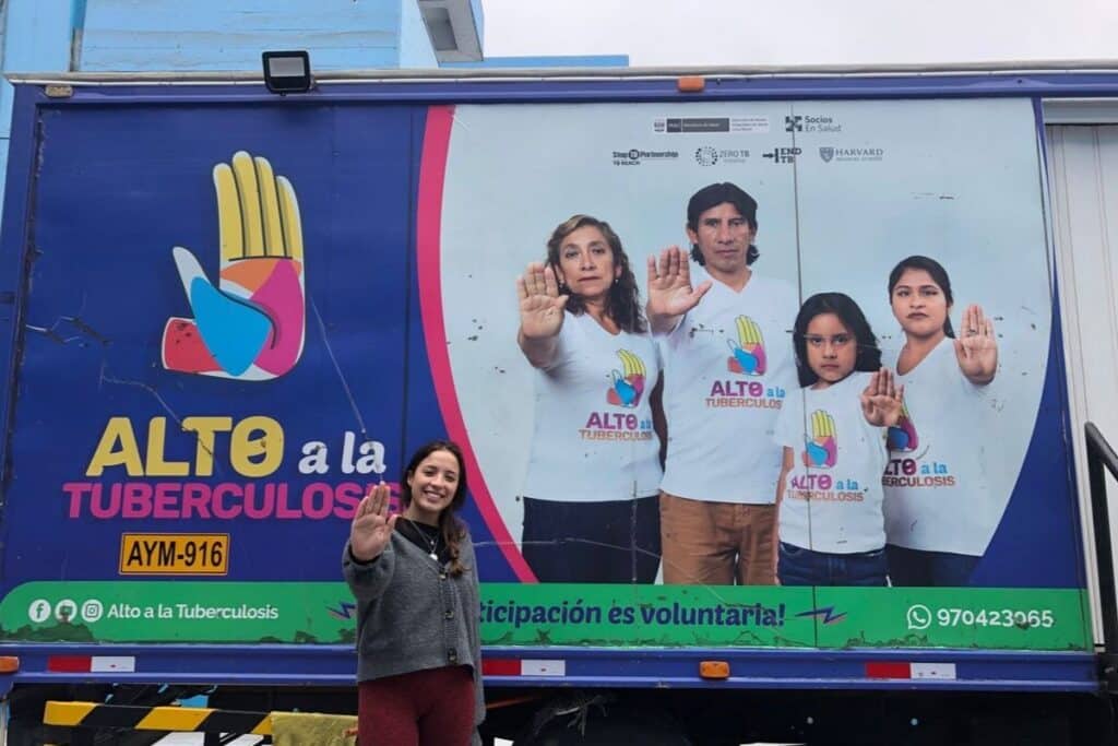 Gabriela posing in front of the campaign Alto a la Tuberculosis (“halt Tuberculosis”) in Lima, Peru