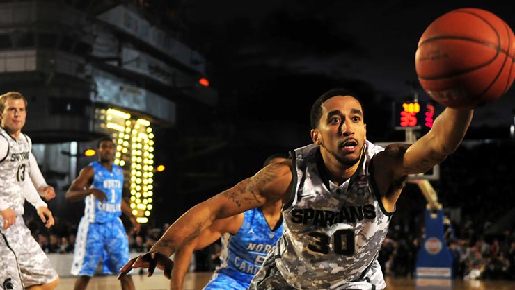 Four men play basketball in an arena