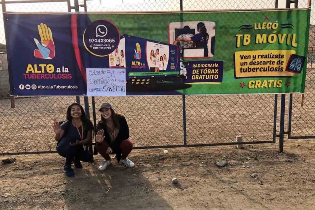 Kneeling in front of a “Stop Tuberculosis” and TB Móvil ad with SES engagement community leader Karla (on the right). 