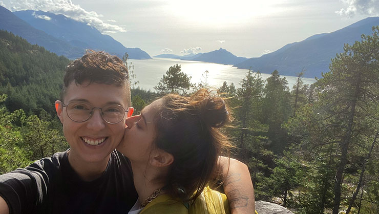 Lydia kisses partner on the cheek in front of beautiful scenery