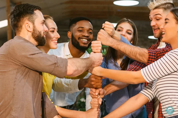 Group of young adults stacking their fists on top of each other.