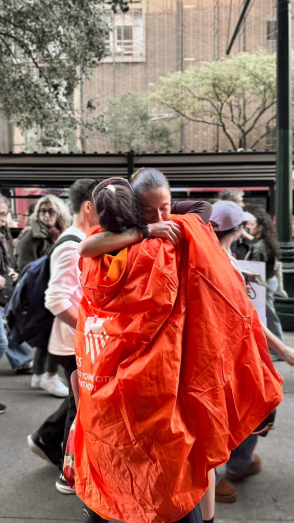 Two girls hugging after just running the NYC marathon