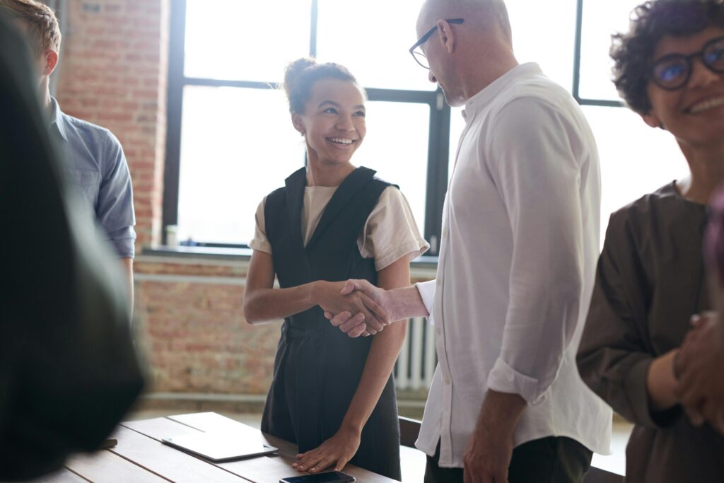 Young woman shaking an older gentleman's hand in a work environment.
